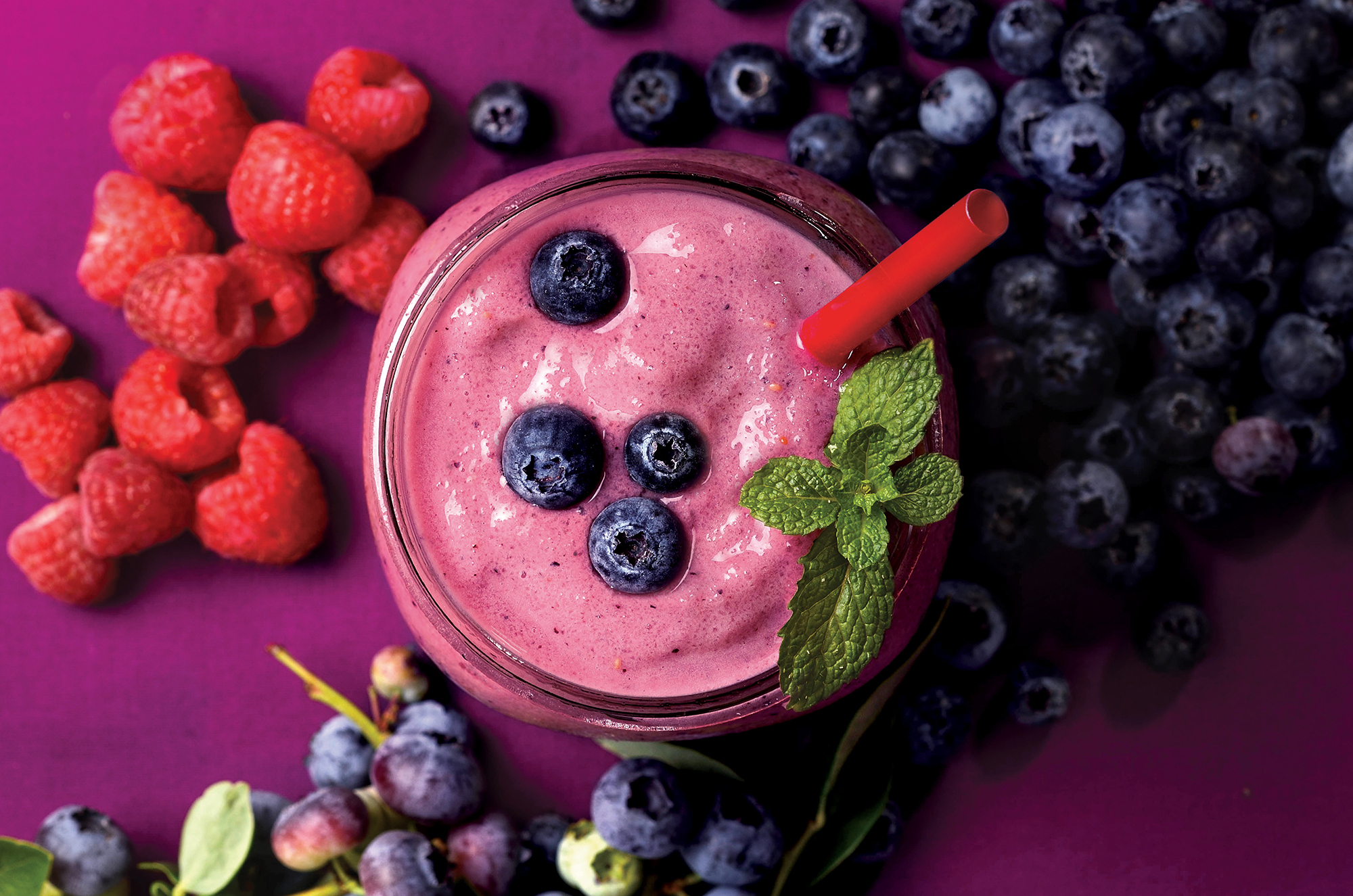 Birds-eye-photo of Nature's Table Rain Forest Rhumba smoothie, surrounded by raspberries and blueberries.